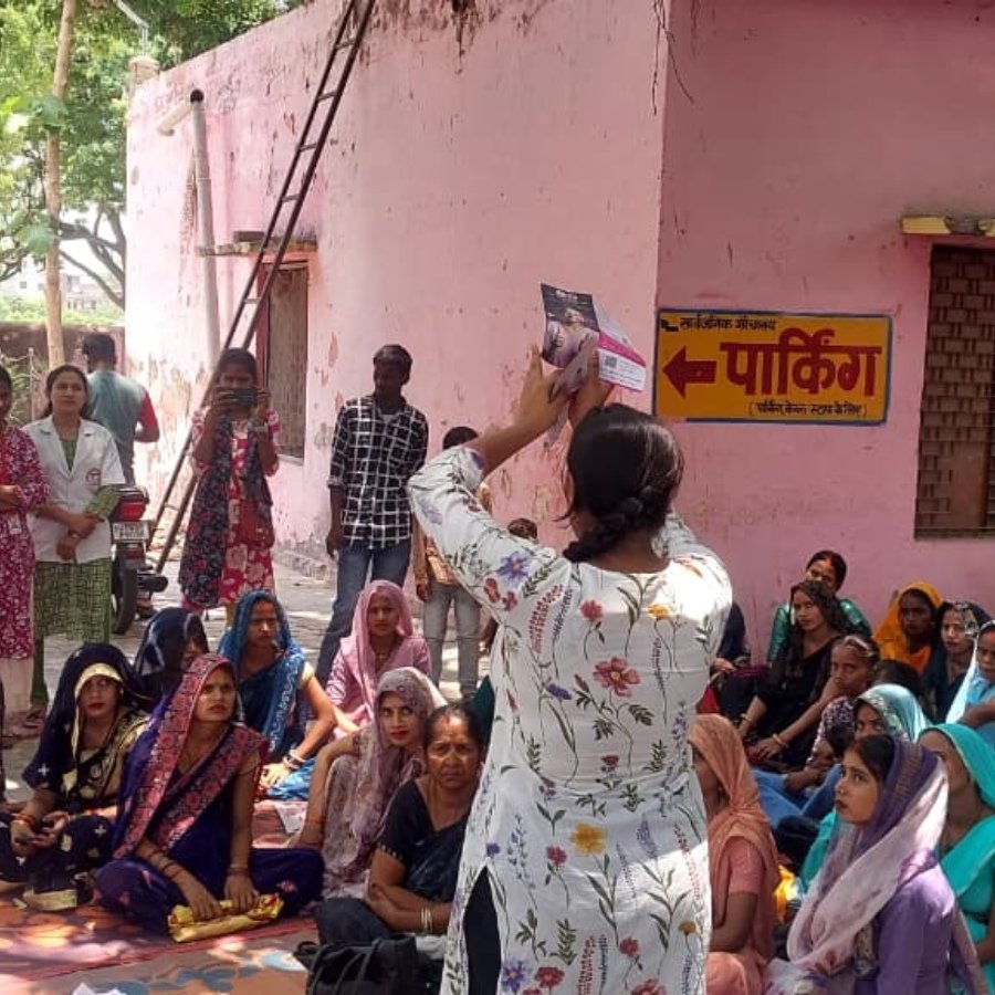An awareness session with women seated together in a rural village setting