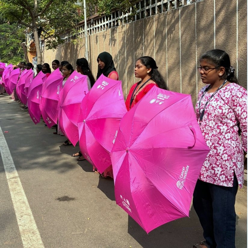 Awareness marchers carrying pink umbrellas through a city street in India